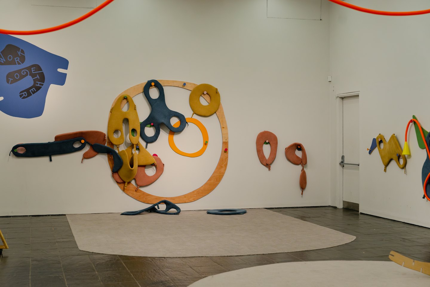Sculture astratte in tessuto e legno esposte su una parete di galleria.